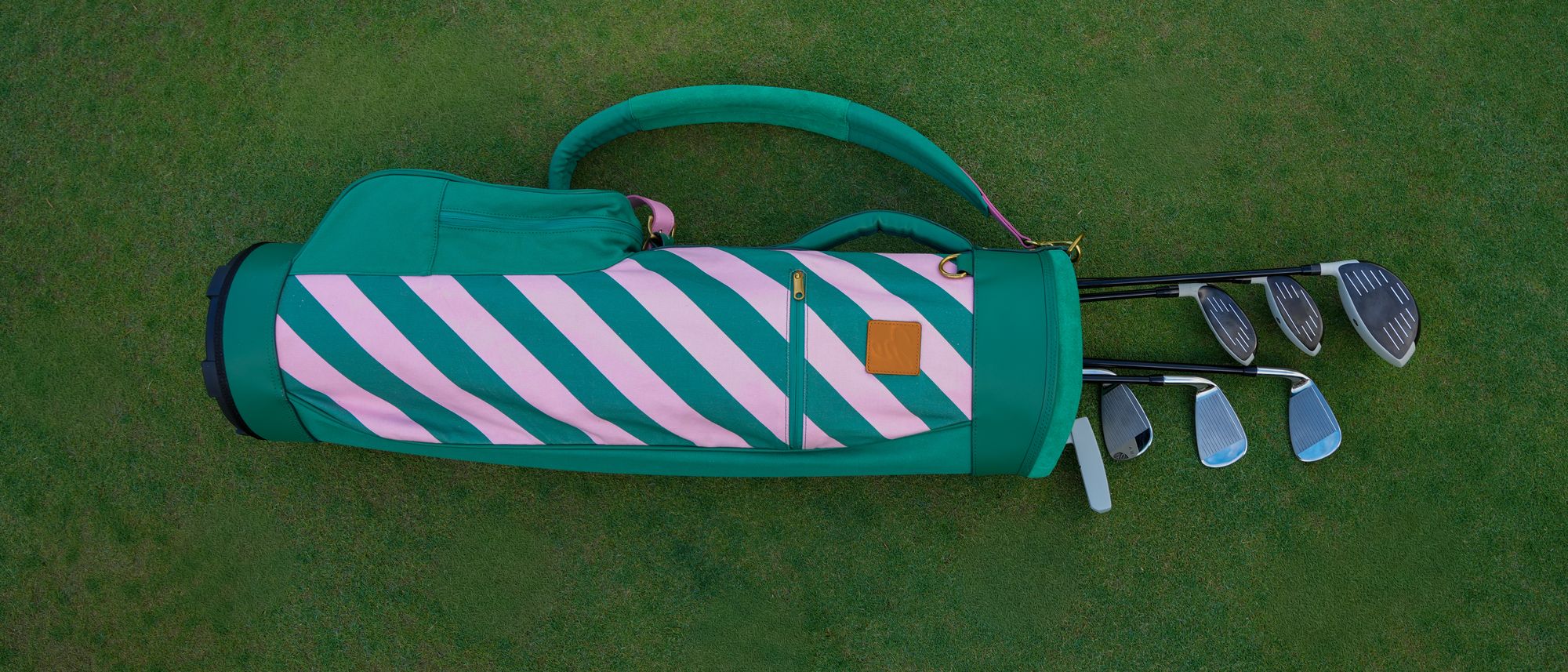 The Gemma bag in green and pink stripe, with clubs, on the fairway